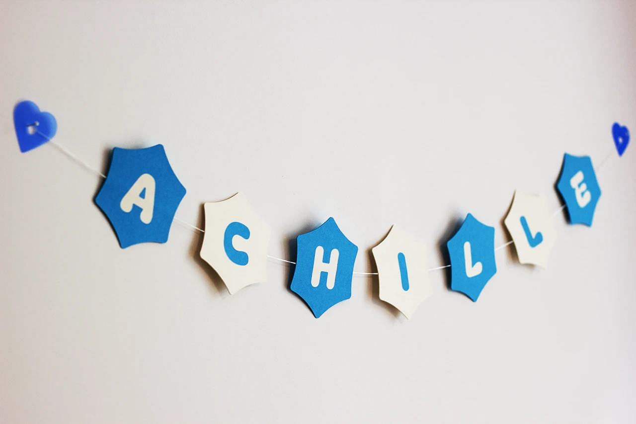 Guirlande prénom « Achille » réalisée en marqueterie papier bleu et blanc à l’atelier Forme contre forme.