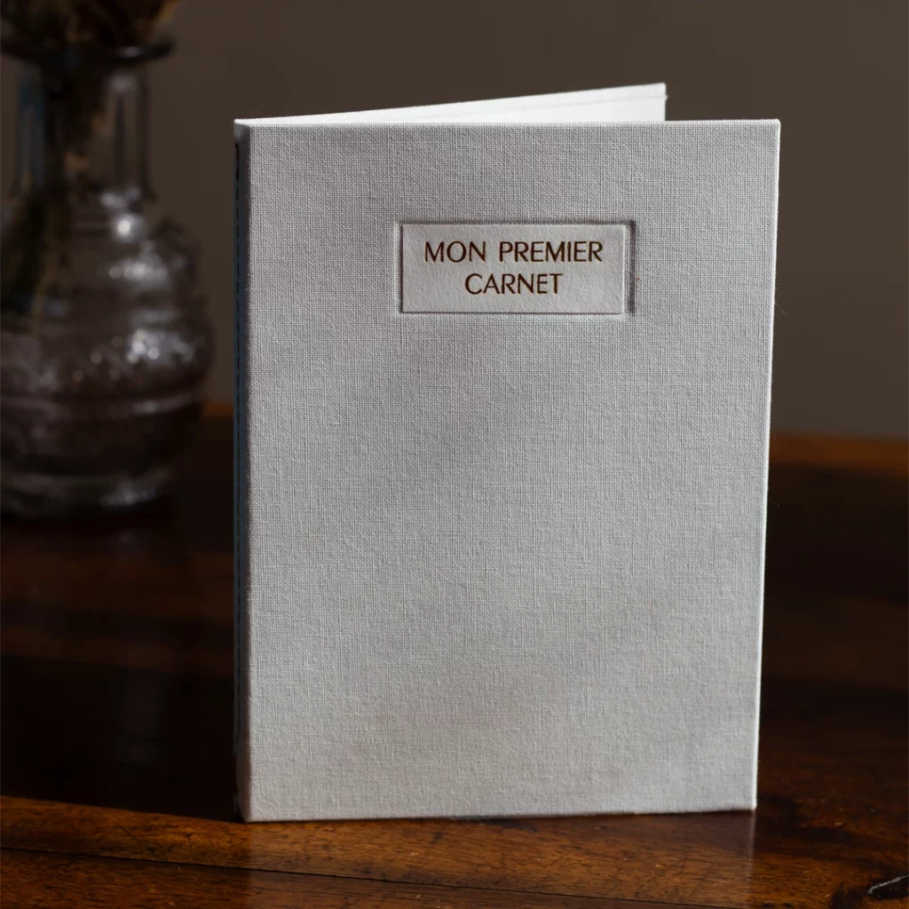 Carnet de naissance personnalisable fermé, toile grise claire, vue de profil 1