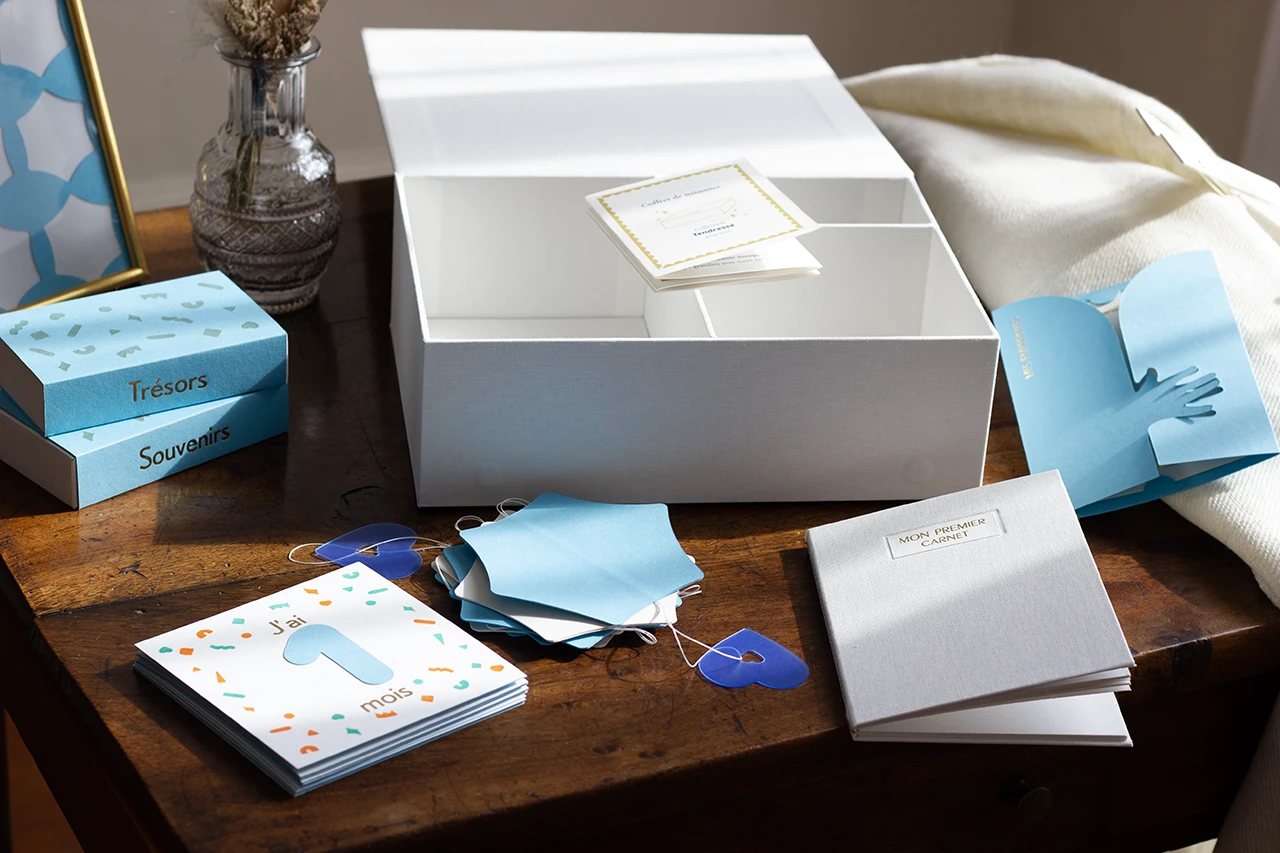 Vue d'ensemble du coffret de naissance personnalisé en toile blanche avec du papier blanc et bleu, issu de la collection Tendresse 2024-2025.