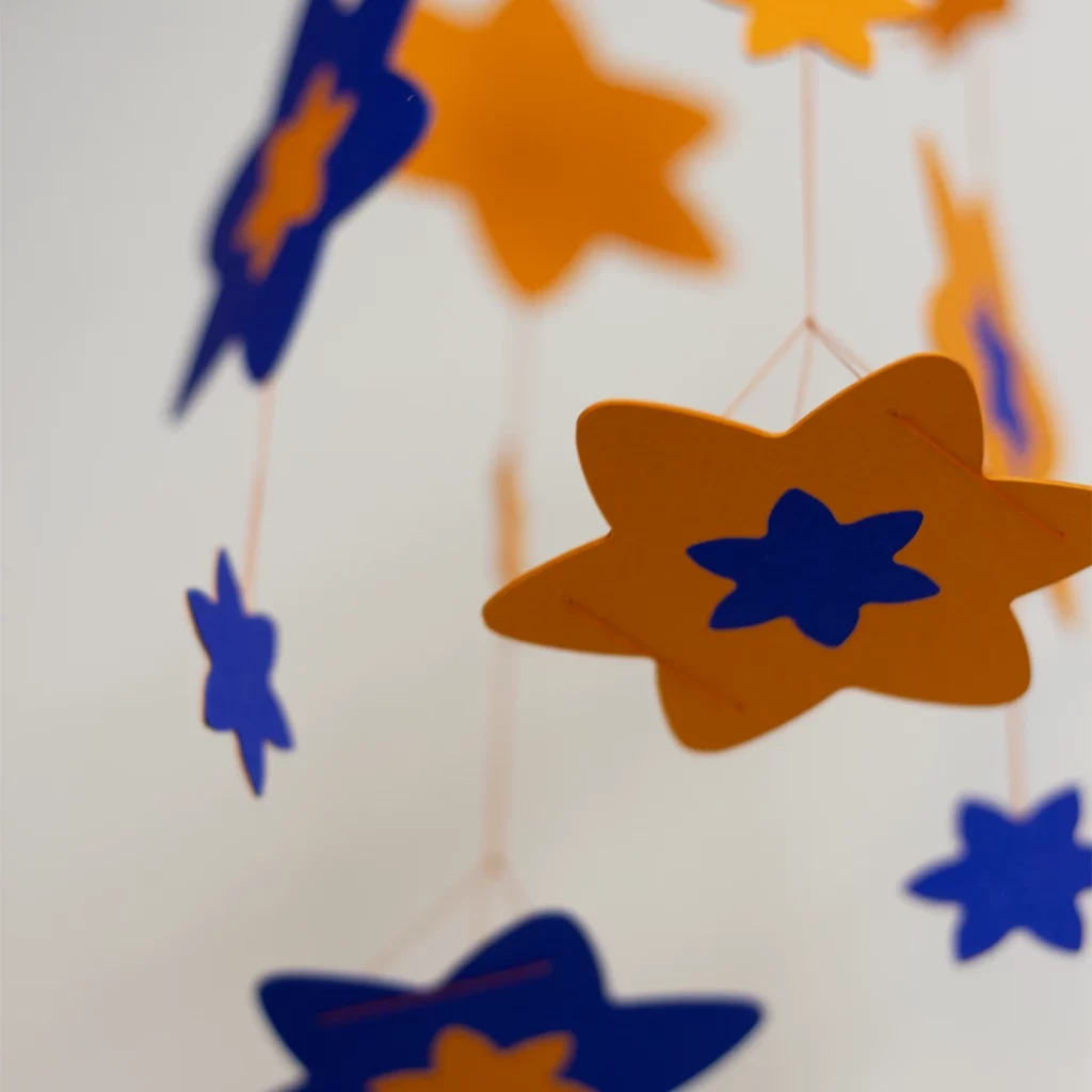 Zoom sur les fleurs de jonquille du mobile bébé en marqueterie de papier personnalisable, couleurs bleu outre-mer et jaune dahlias 2