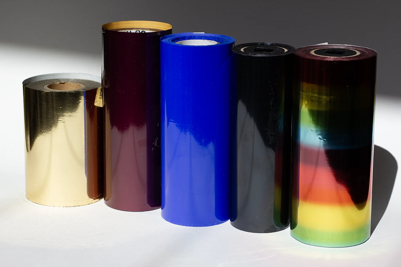 Échantillons de films de dorure (de gauche à droite) : doré, bordeaux, bleu, noir et arc-en-ciel.