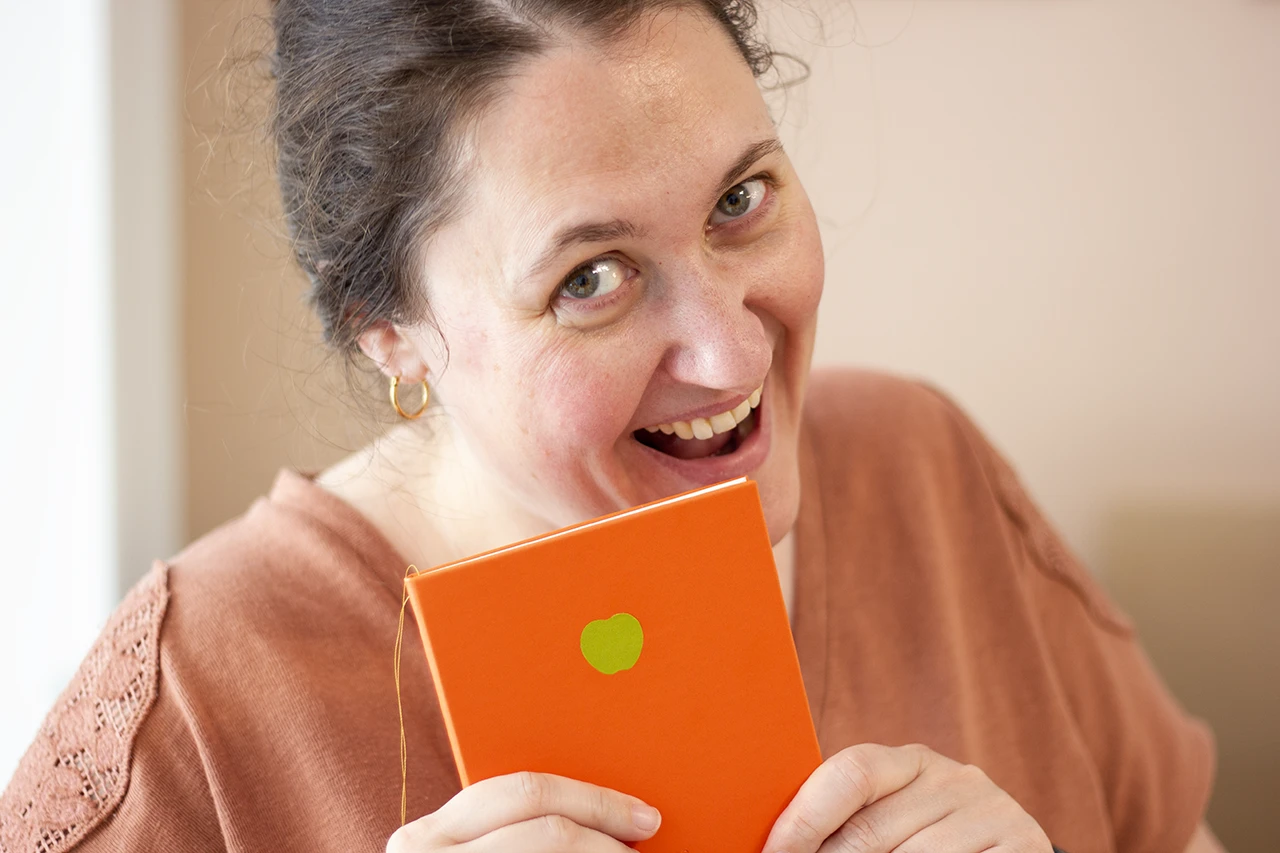 Alexandrine croquant dans son carnet fait main en cuir de pomme.