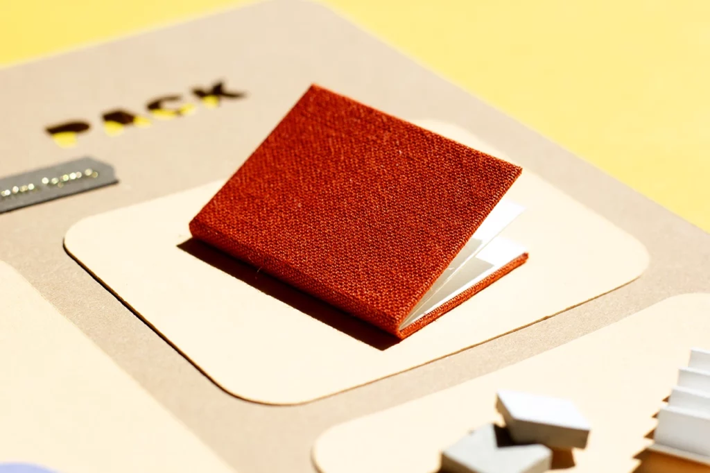 Détail du starter pack : carnet fait main avec une couverture en toile de reliure orange — vue 2.