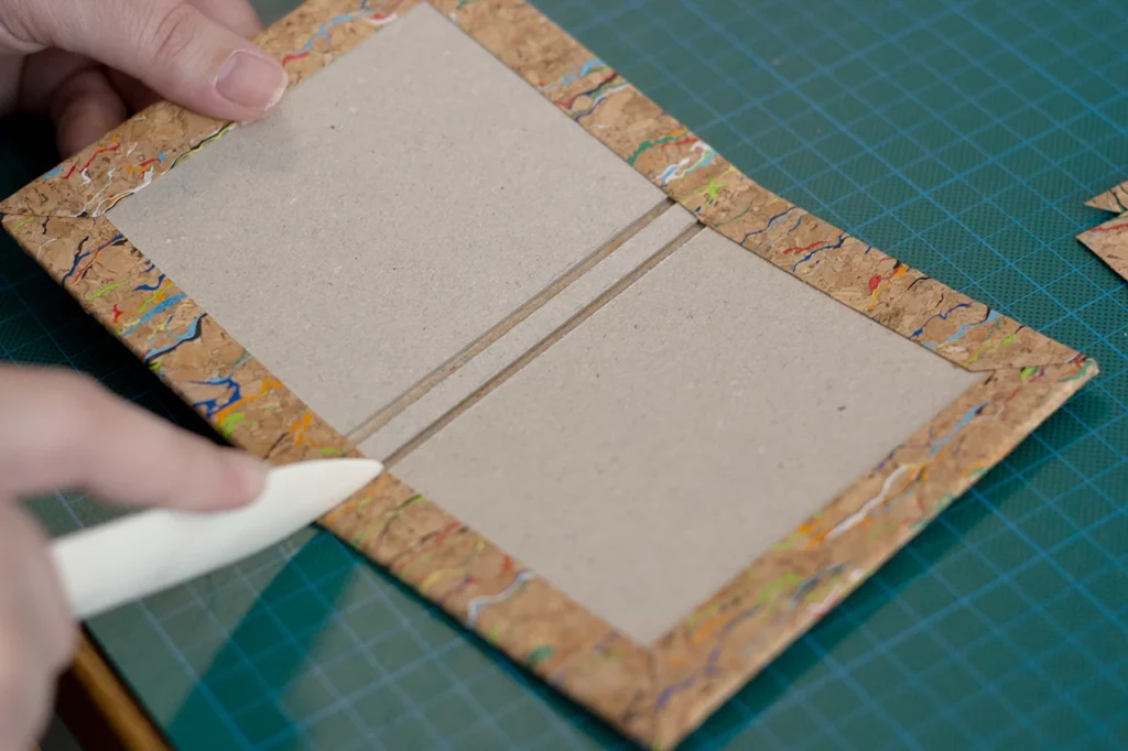 Finition du rembordage à l’aide d’un plioir, sur une couverture en toile de liège. Finition du rembordage à l’aide d’un plioir, sur une couverture en toile de liège.