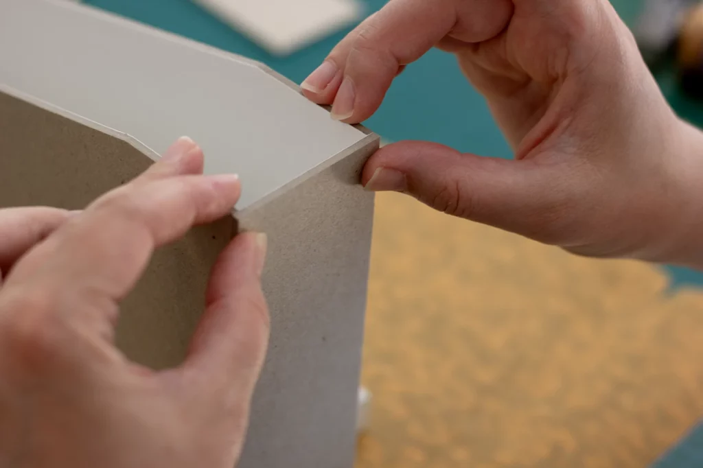 Mise en place du carton gris pour la création d’un porte-revues fait main, recouvert de toile de liège. Mise en place du carton gris pour la création d’un porte-revues fait main, recouvert de toile de liège.