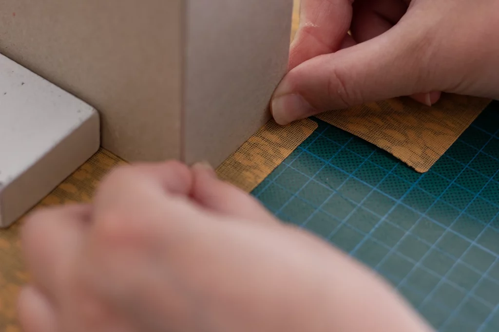 Zoom sur la mise en place du carton gris pour un porte-revues fait main en toile de liège. Zoom sur la mise en place du carton gris pour un porte-revues fait main en toile de liège.