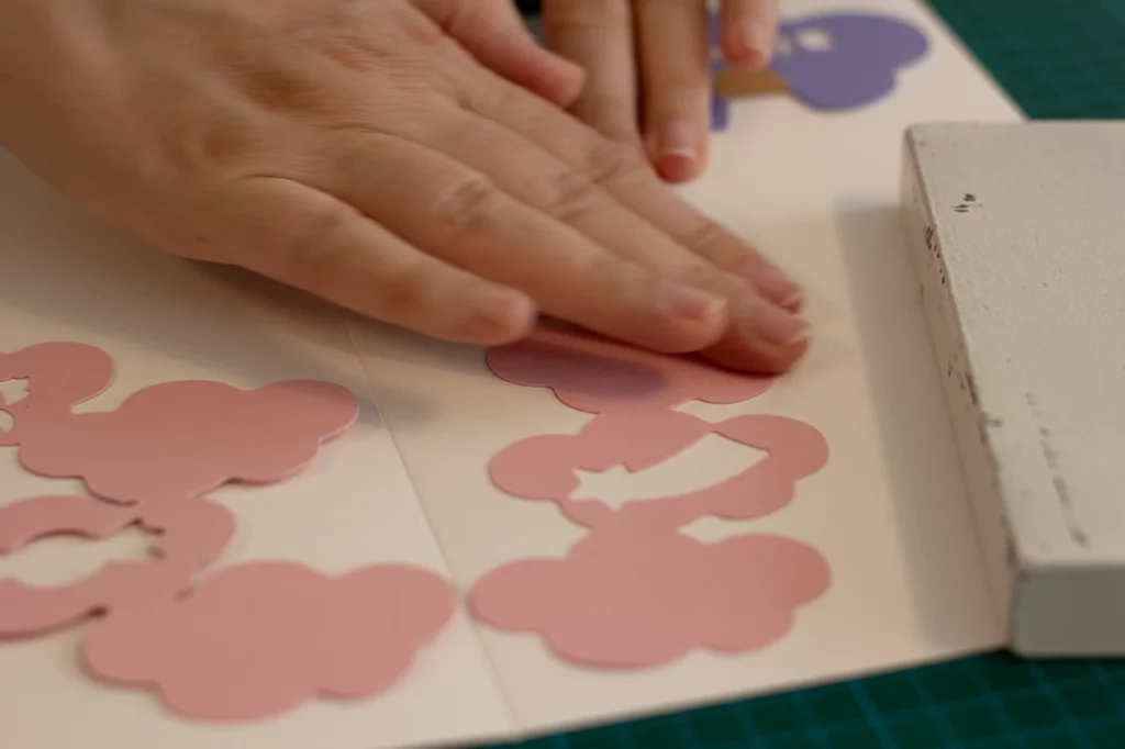 Zoom sur le collage des nuages mis sous presse pour séchage, sur le plateau de jeu "Au royaume des licornes".