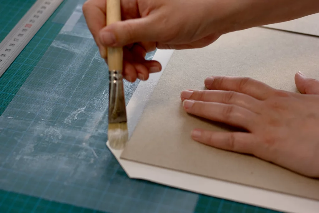 Rembordage au pinceau sur la couverture en toile blanche de reliure (Winter & Company).