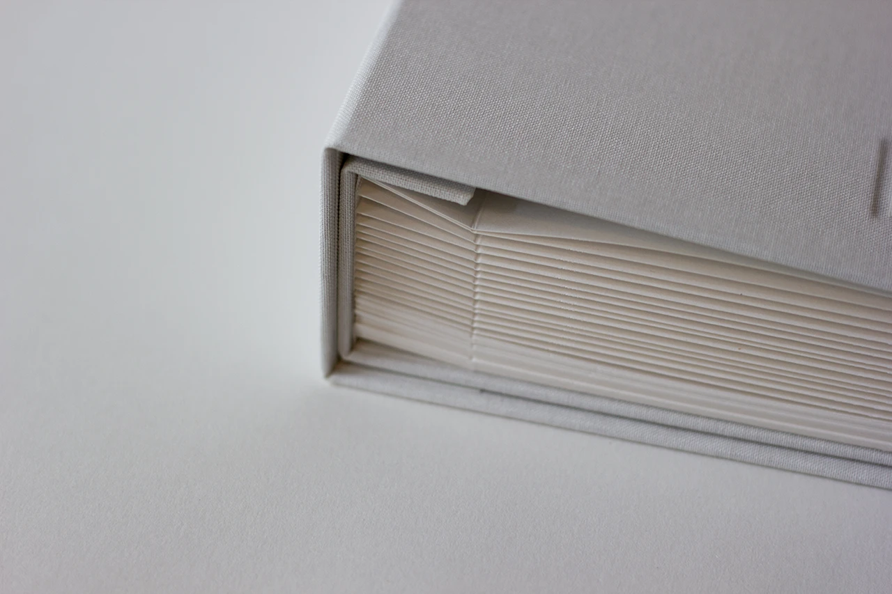Zoom sur la partie inférieure du livre d’or, montrant la couverture et le rabat intérieur qui maintient les feuilles.