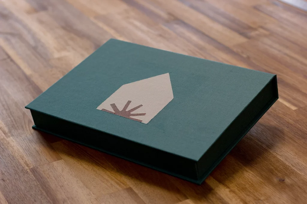 Boîte à clapet fermée, en marqueterie de toile trois couleurs — vert forêt, gris et marron simili cuir — réalisée lors d’un atelier d’artisanat personnalisé.