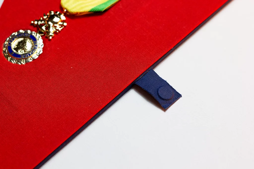 Zoom sur la languette du fourreau en marqueterie de toile, déployé hors du cadre.