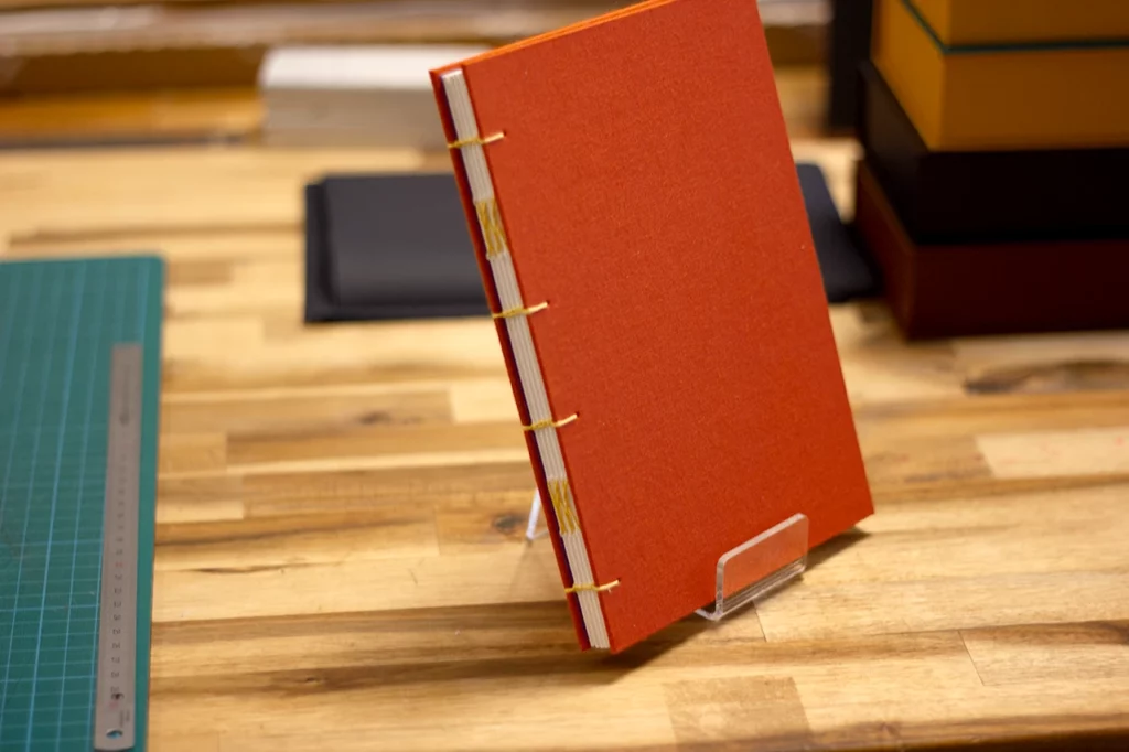 Carnet aquarelle avec reliure copte en fil de lin ciré jaune moutarde artisanal et toile de reliure orange.