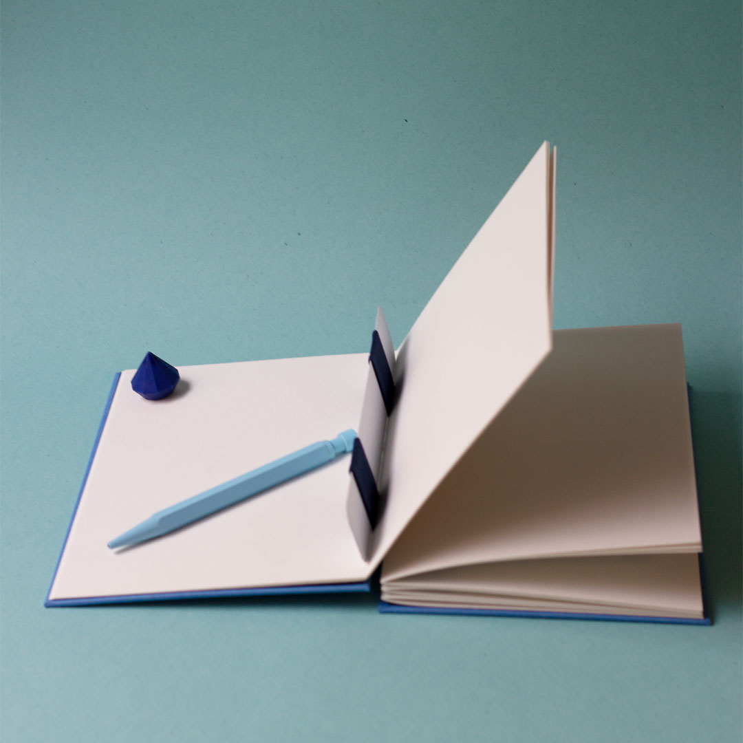 Carnet ouvert avec une reliure australienne à charnière piano inversée, style plat, montrant la charnière intérieure et le gond plat qui maintient les cahiers.