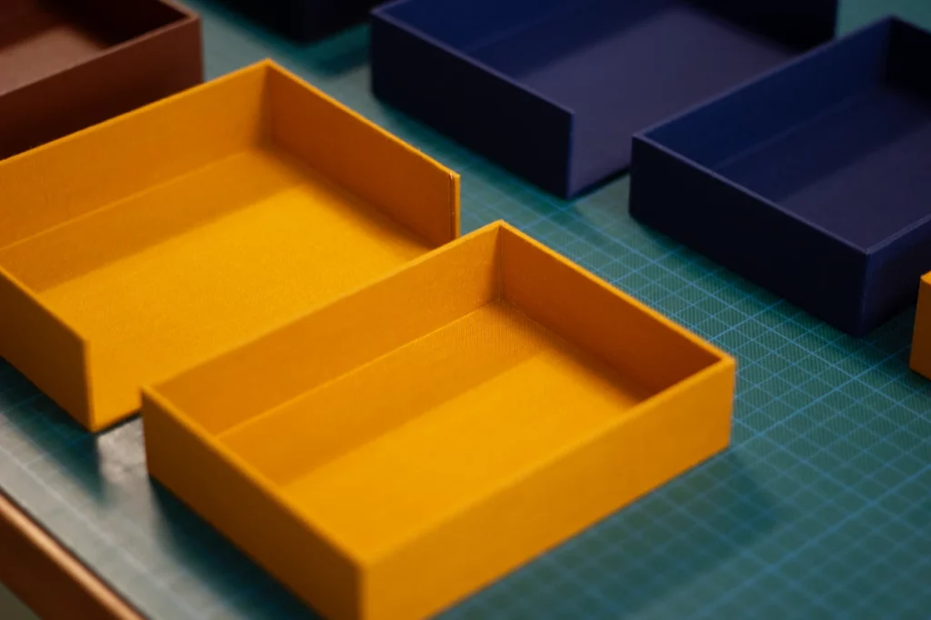 Préparation des différentes parties des boîtes à clapet, recouvertes de toile de reliure Le Marais.