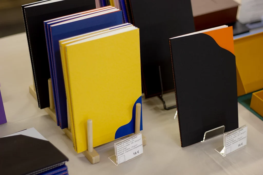 Vue des carnets bicolores format A5, à formes organiques ou géométriques, présentés lors du salon de l’artisanat à La Teste-de-Buch.