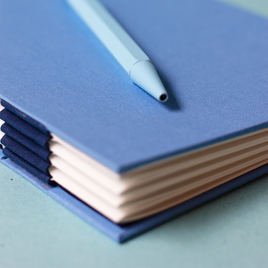 Zoom sur le bas du dos du carnet, présentant une reliure australienne à charnière piano inversée, style plat.