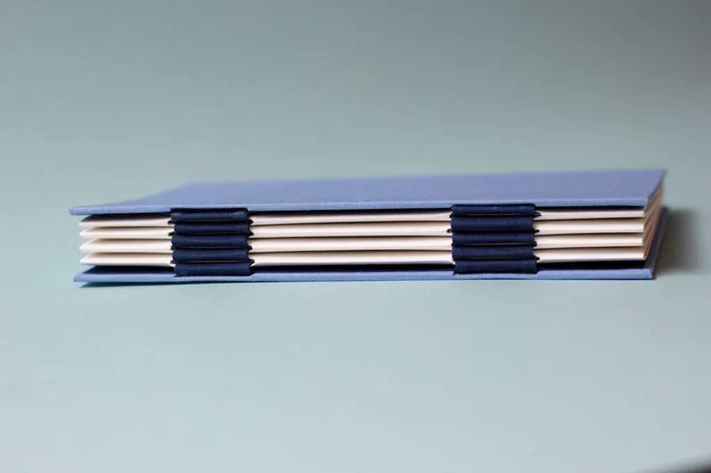 Zoom sur le dos du carnet avec une reliure australienne à charnière piano inversée, style plat.