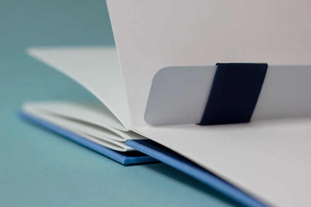 Zoom sur le haut du carnet avec une reliure australienne ouvert, laissant apparaître le gond plat pouvant servir de marque-page.