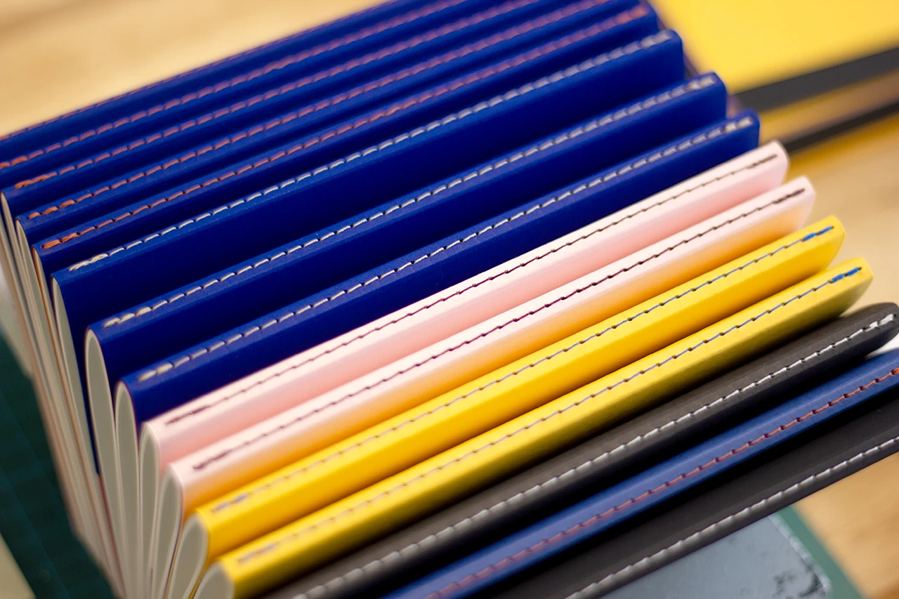 Zoom sur les carnets bicolores après reliure Singer, avant mise sous presse.