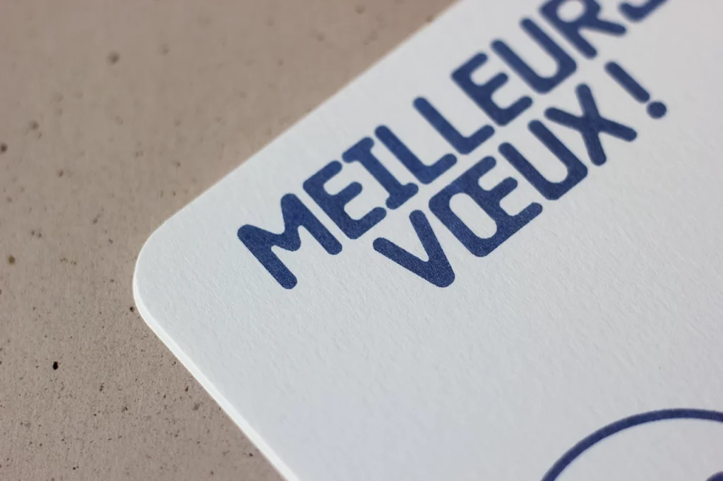 Zoom sur la carte de vœux « Bonhomme 26 », imprimée en letterpress avec une encre bleue pailletée.