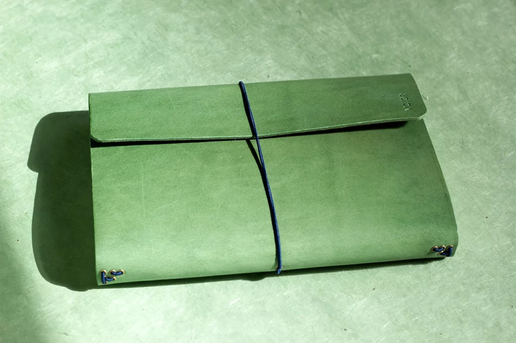 Carnet de voyage avec couverture en cuir italien pleine fleur, couleur bambou, tannage végétal et fermeture par élastique rond bleu — Atelier Forme contre forme, Bordeaux.