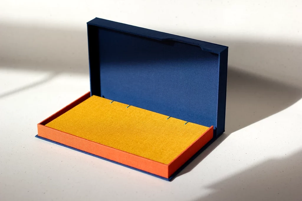 Coffret clamshell ouvert sur mesure, toile du Marais bleu marine et orange — réalisé à Bordeaux — rayon de soleil, vue d’ensemble bis.