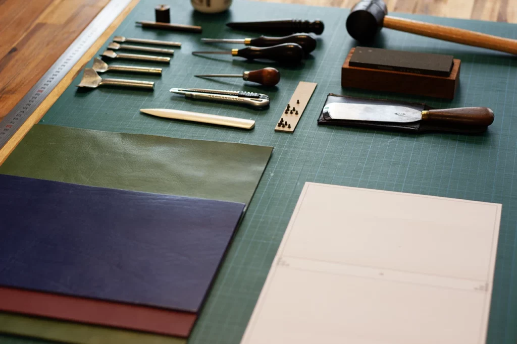 Matériel indispensable pour la fabrication d’un carnet en cuir (couteau à parer, lissette brunissoir, abat-carre, emporte-pièce, alêne) — Atelier Forme contre forme, Bordeaux.