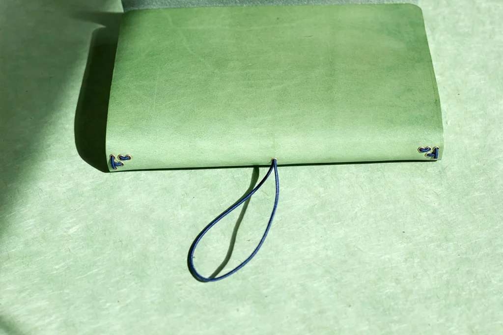 Vue du système de fermeture centrale au dos du carnet en cuir avec élastique — Atelier Forme contre forme, Bordeaux.