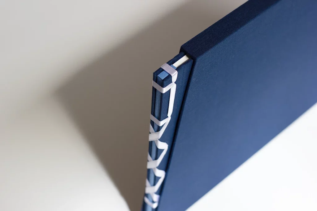 Livre d’or de mariage en reliure japonaise, ruban satiné blanc, toiles bleu marine et bleu clair, inséré dans son fourreau sur mesure — Atelier Forme contre forme, Bordeaux.