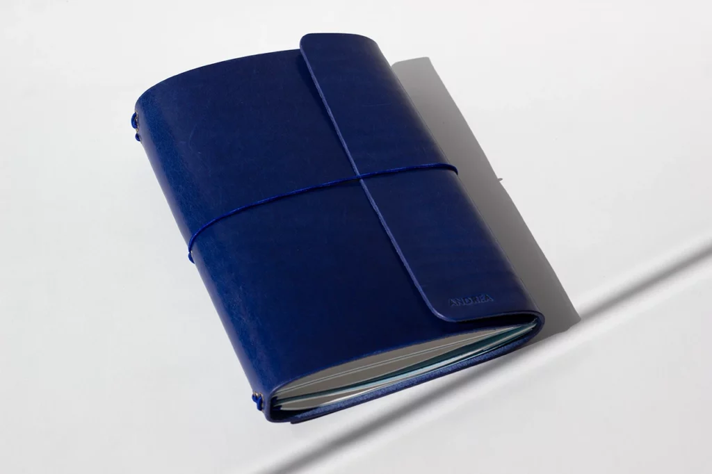 Carnet de voyage en cuir italien pleine fleur, couleur cobalt, tannage végétal et fermeture par élastique rond bleu — Atelier Forme contre forme, Bordeaux.