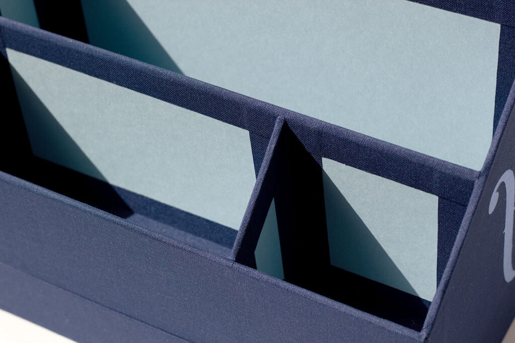 Détail des compartiments d’un organiseur de bureau sur mesure en toile du Marais bleu marine, intérieur en papier Fedrigoni Celeste — Atelier Forme contre forme, Bordeaux.