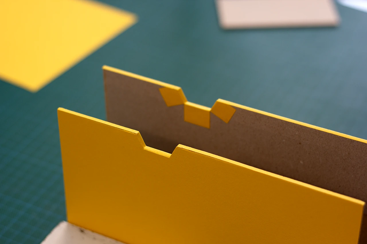 Fourreau rigide sur mesure (Slipcase) en cours de façonnage avec des encoches de préhension en forme géométrique — Atelier Forme contre forme, Bordeaux.