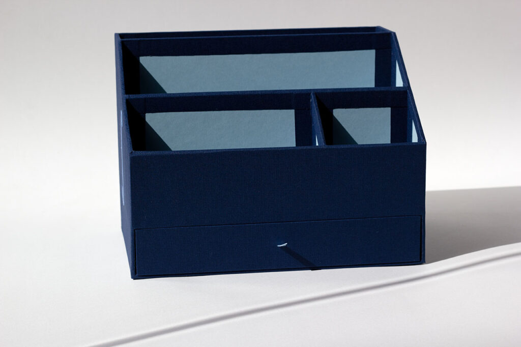 Organiseur de bureau sur mesure avec quatre compartiments et un tiroir de rangement, en toile du Marais bleu marine, intérieur en papier Fedrigoni Celeste — Atelier Forme contre forme, Bordeaux.