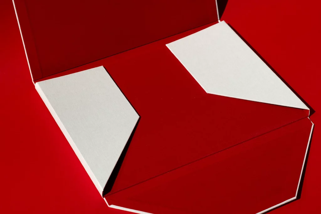 Portefeuille à quatre rabats ouvert avec deux rabats refermés, réalisé en toile de reliure du Marais Nude et rouge — Atelier Forme contre forme, Bordeaux.