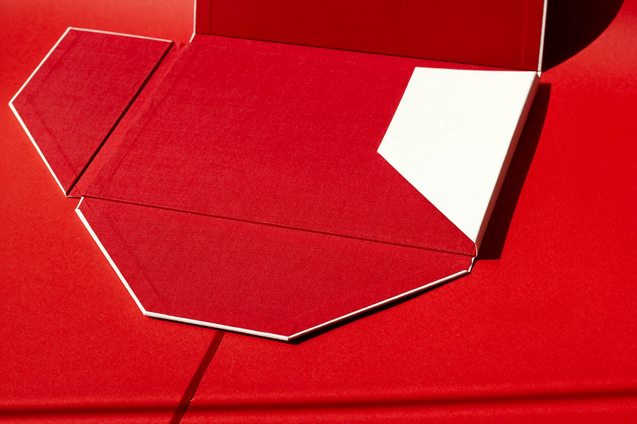 Portefeuille à quatre rabats ouvert avec un rabat refermé, réalisé en toile de reliure du Marais Nude et rouge, avec ruban satinée rouge — Atelier Forme contre forme, Bordeaux.