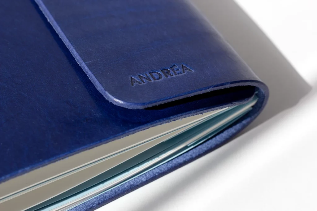 Zoom sur le marquage à sec d’un prénom sur le rabat d’un carnet de voyage en cuir personnalisé — Atelier Forme contre forme, Bordeaux.
