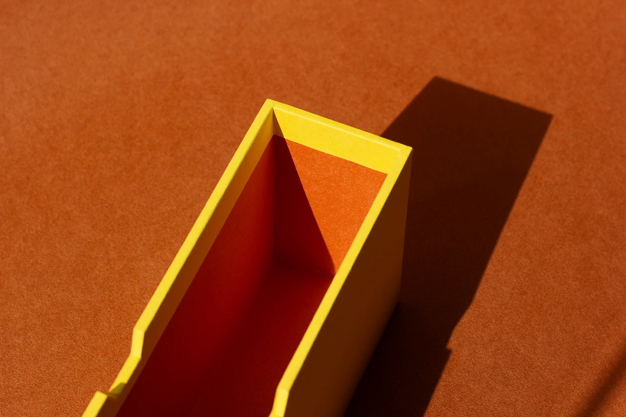 Zoom sur les finitions d'un fourreau rigide sur mesure, papier Fedrigoni Materica Terra Gialla et Terra Rossa — Atelier Forme contre forme, Bordeaux.