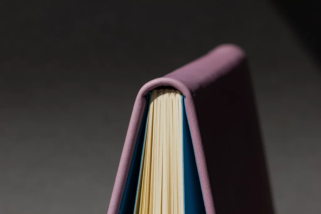 Carnet en cuir mauve à dos carré cousu-collé, avec pages de garde bleues et fermeture élastique — Atelier Forme contre forme, Bordeaux.