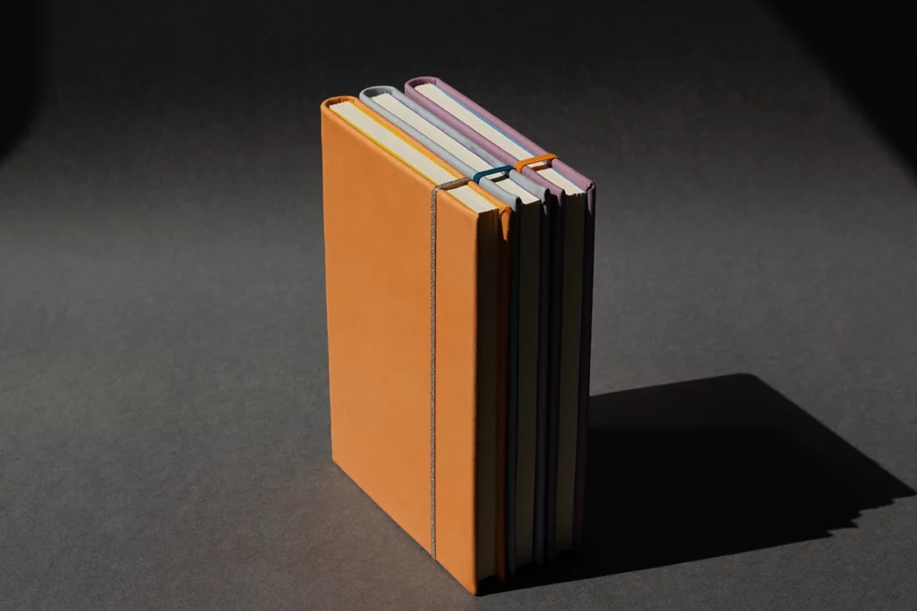Carnets en cuir artisanaux réalisés lors d’un atelier sur mesure, en cuir sellier végétal pastel orange, bleu et mauve — Atelier Forme contre forme, Bordeaux.